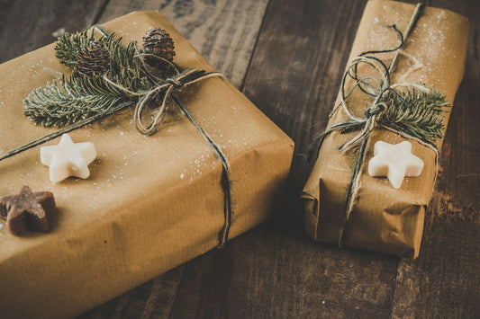 Two kraft-paper wrapped gifts tied with twine and fir sprigs on a wooden table