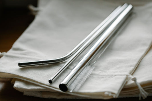 Stainless steel straws and a cleaning brush on folded cotton bags