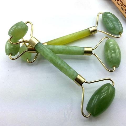 Three jade facial rollers in different shades of green with brass-colored frames